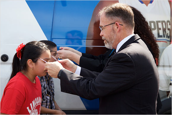 Chris Steinhauser, Superintendent of the Long Beach Unified School District, helps children with their new glasses at George Washington Middle School in Long Beach.