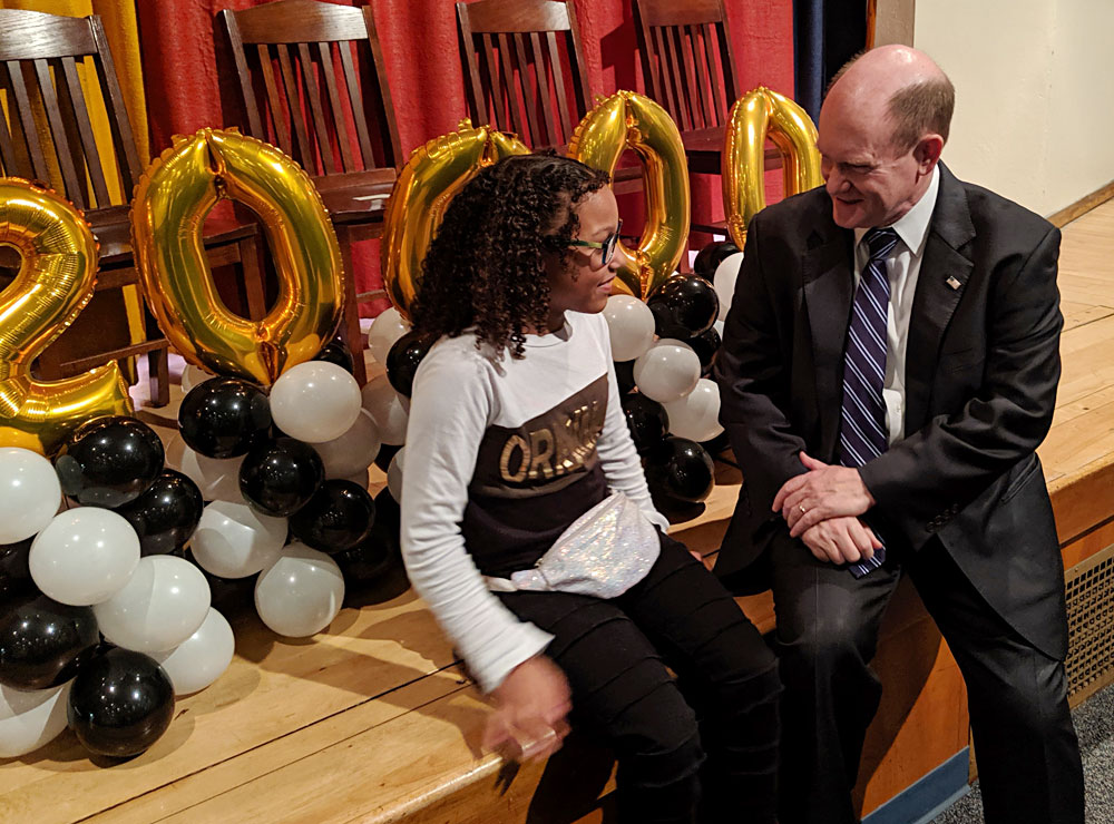 Senator Chris Coons chats with the 200,000th child to receive glasses from Vision To Learn