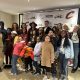 A group of adults and children stand in front of a step and repeat with Vision To Learn, Cleveland Cavaliers, and Kaulig Giving logos.