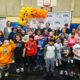 A group of elementary school students pose for a photo with Vision To Learn founder Austin Beutner, New York Times columnist Nick Kristof, Jim & Sue Kelly, and representatives from Portland Public Schools and Warby Parker.