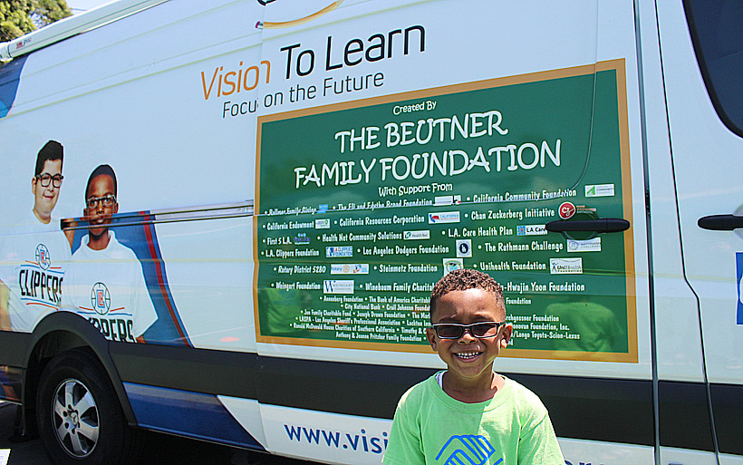 Boy showing off new glasses in front of mobile clinic