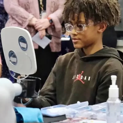 Middle school boy contemplating new glasses in mirror