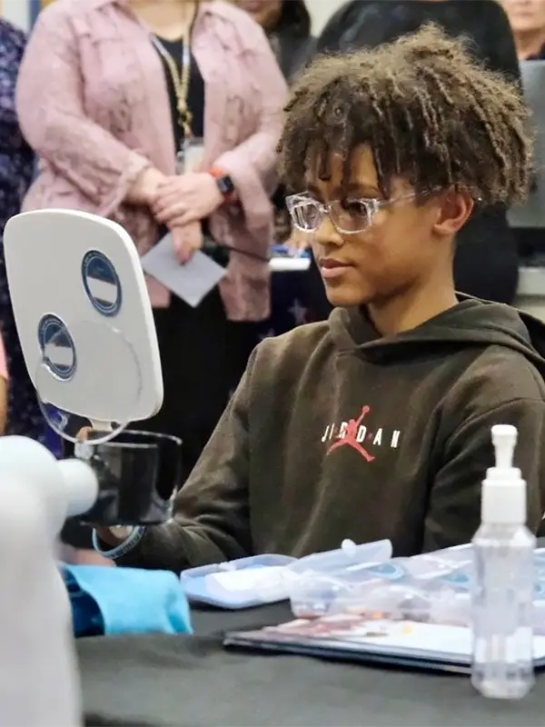 Middle school boy contemplating new glasses in mirror