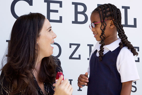 Gillian Zucker, President of Business Operations for the Los Angeles Clippers, with a girl who just received her new glasses at Warren Lane Elementary School in Inglewood.