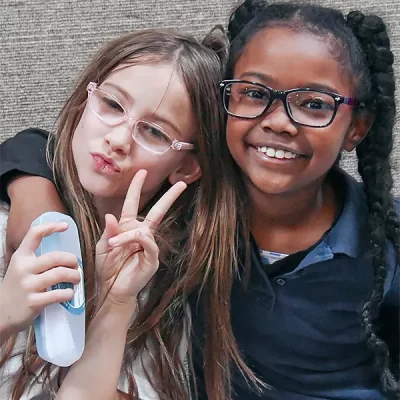 Two girls showing off their smiles with new glasses
