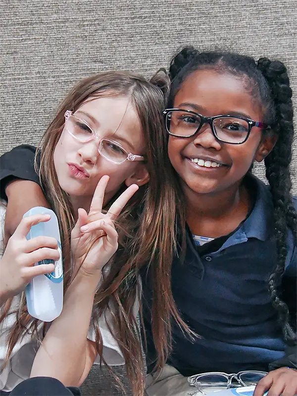 Two girls showing off their smiles with new glasses